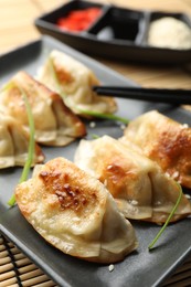 Photo of Delicious fried gyoza dumplings with sesame seeds served on table, closeup