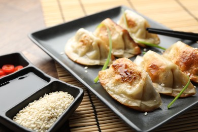 Photo of Delicious fried gyoza dumplings with sesame seeds served on table, closeup