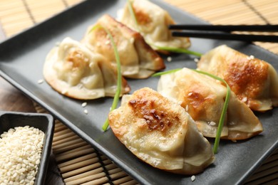 Photo of Delicious fried gyoza dumplings with sesame seeds served on table, closeup