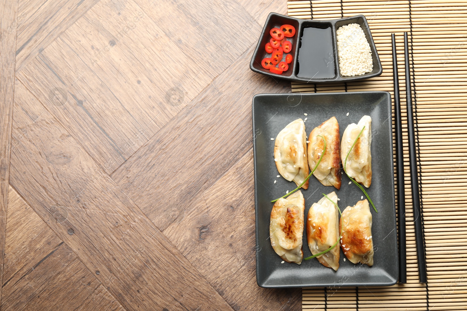 Photo of Delicious fried gyoza dumplings served on wooden table, flat lay. Space for text