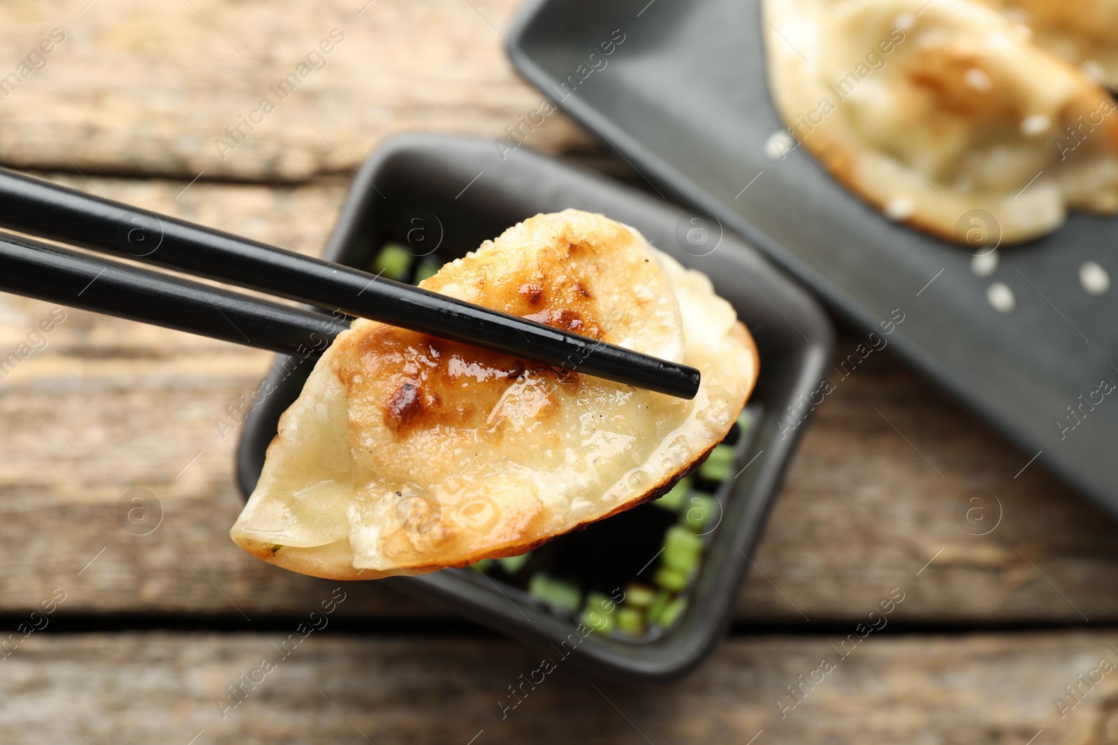 Photo of Eating fried gyoza dumplings at wooden table, closeup