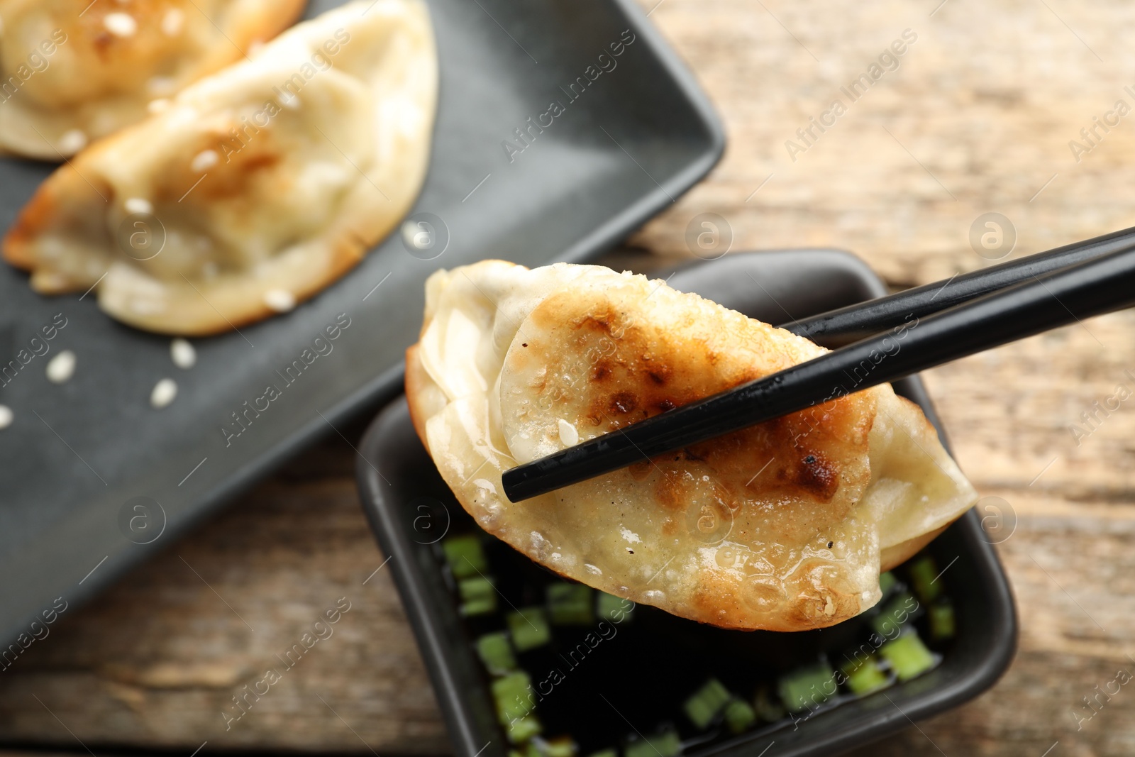 Photo of Eating fried gyoza dumplings at wooden table, closeup