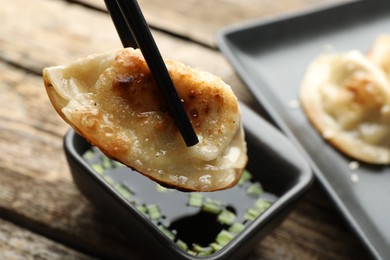 Photo of Eating fried gyoza dumplings at wooden table, closeup