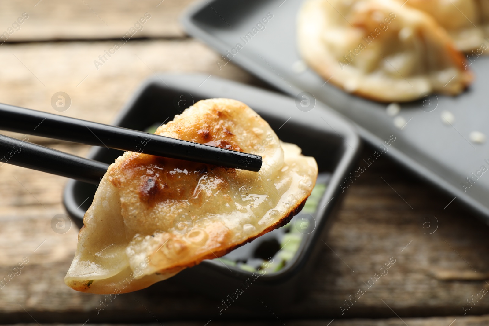 Photo of Eating fried gyoza dumplings at wooden table, closeup