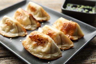 Photo of Fried gyoza dumplings with sesame seeds on wooden table, closeup