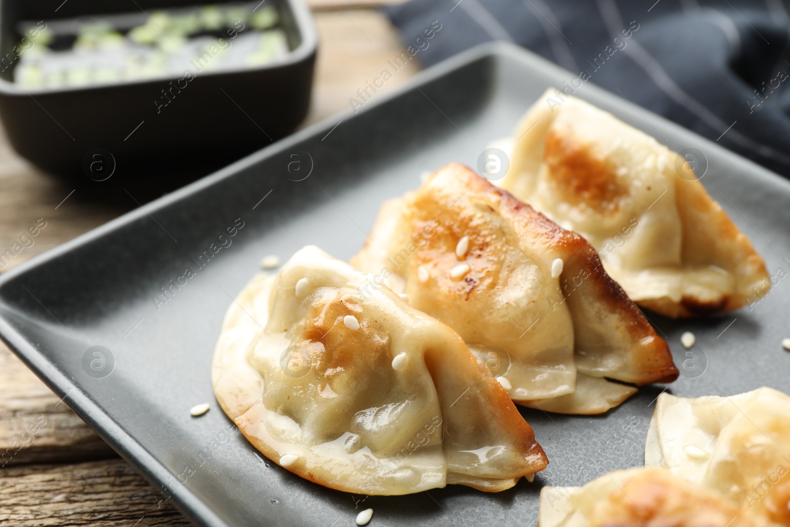 Photo of Fried gyoza dumplings with sesame seeds on wooden table, closeup