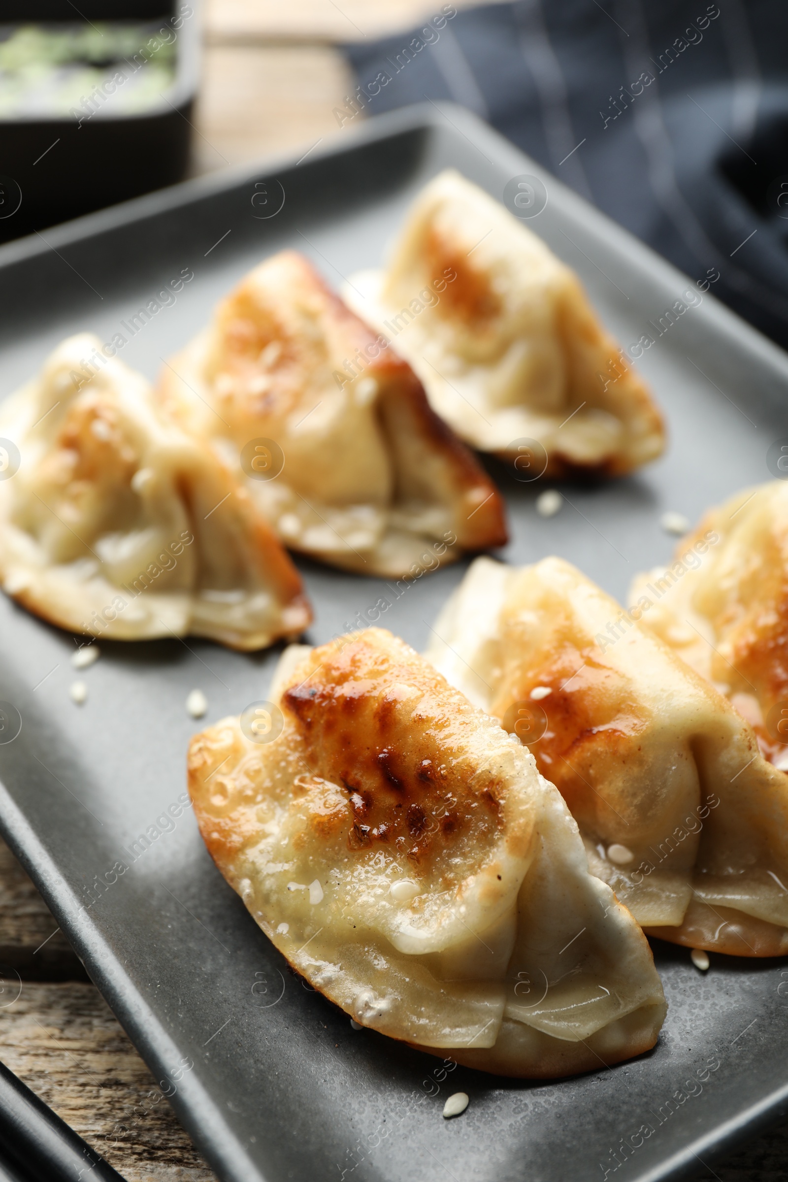 Photo of Fried gyoza dumplings with sesame seeds on wooden table, closeup