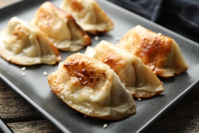 Photo of Fried gyoza dumplings with sesame seeds on wooden table, closeup