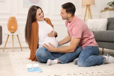 Photo of Man trying to feel baby kicks in his pregnant wife's belly at home