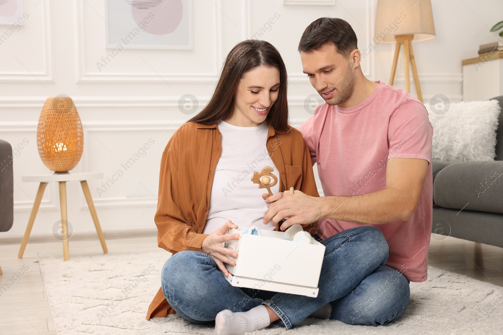 Photo of Pregnant woman and her husband with box of baby toys at home