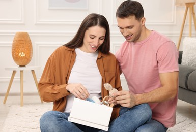 Photo of Pregnant woman and her husband with box of baby toys at home