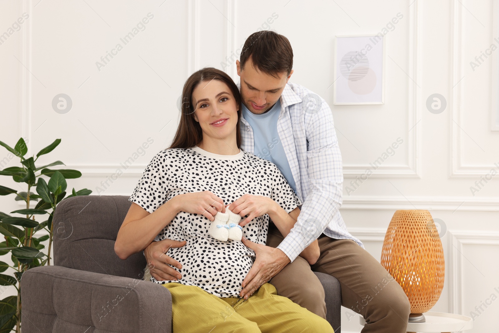 Photo of Pregnant woman and her husband with baby booties at home