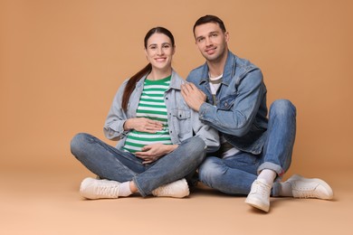 Photo of Pregnant woman and her husband on beige background