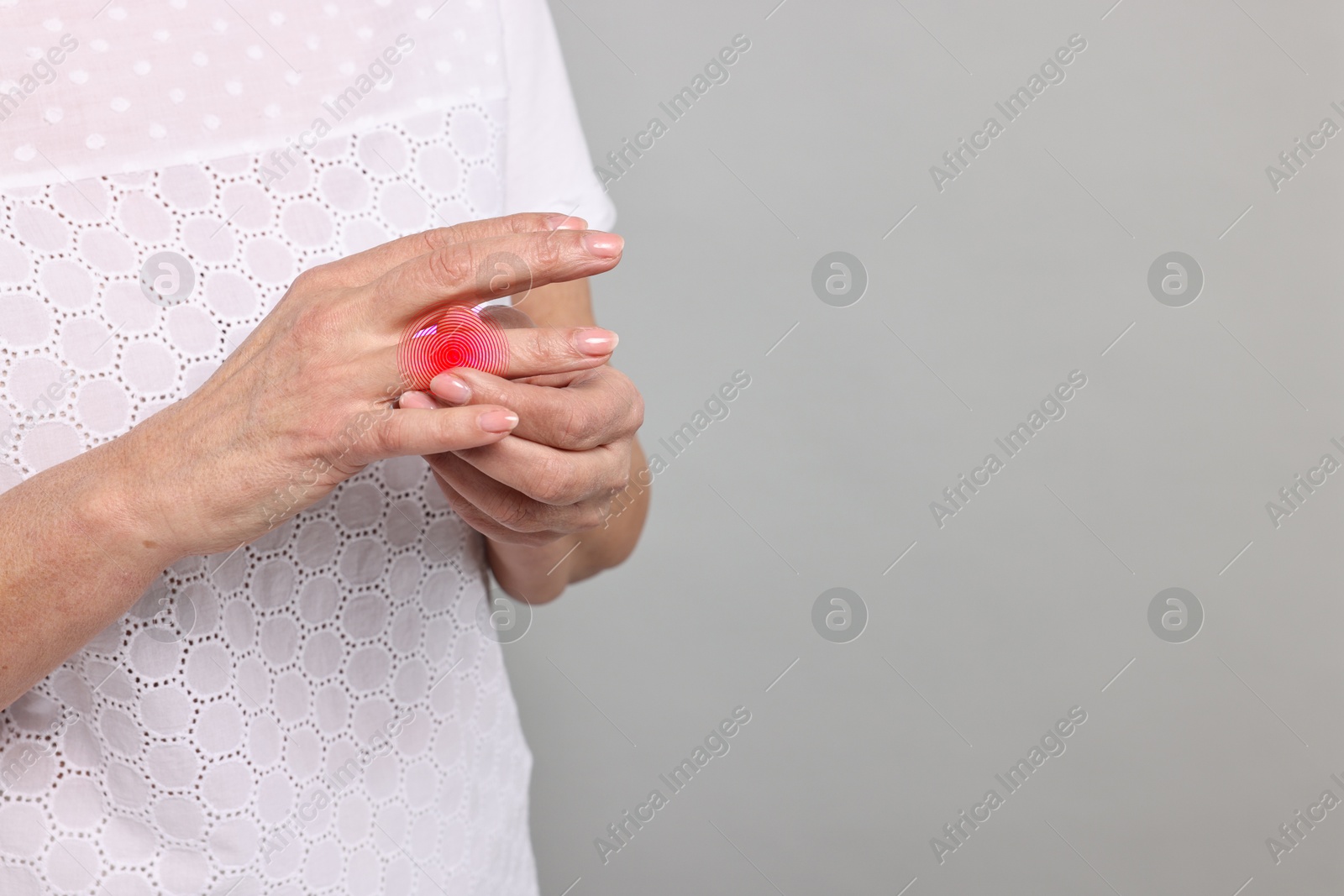 Image of Woman with joint inflammation on grey background, closeup. Red area on finger