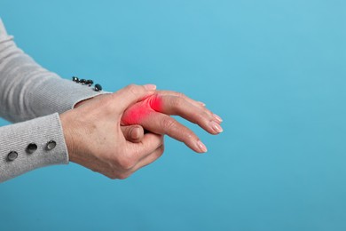 Image of Woman with joint inflammation on light blue background, closeup. Red areas on fingers