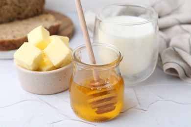 Photo of Sweet honey, butter and milk on white table, closeup