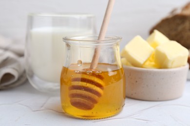 Sweet honey, butter and milk on white table, closeup