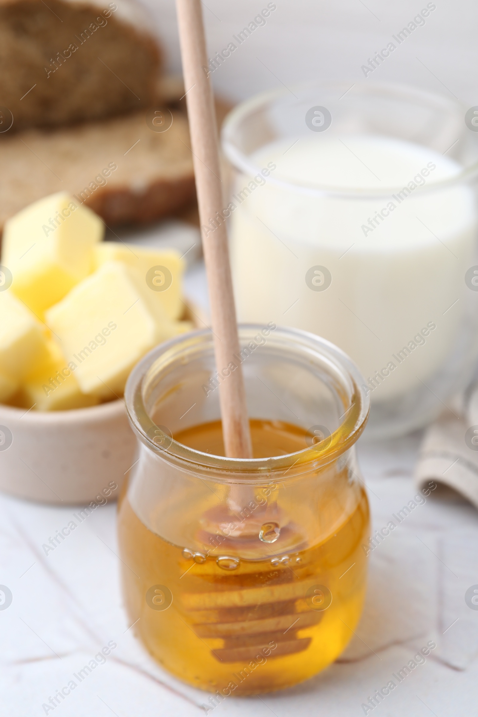 Photo of Sweet honey, butter and milk on white table, closeup