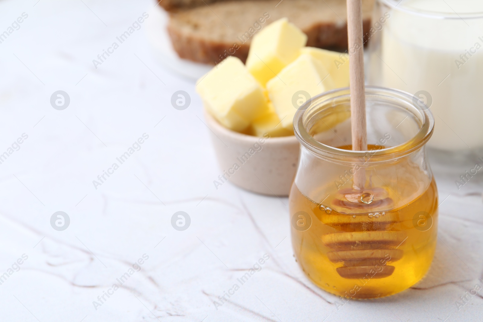 Photo of Sweet honey, butter and milk on white table, closeup. Space for text