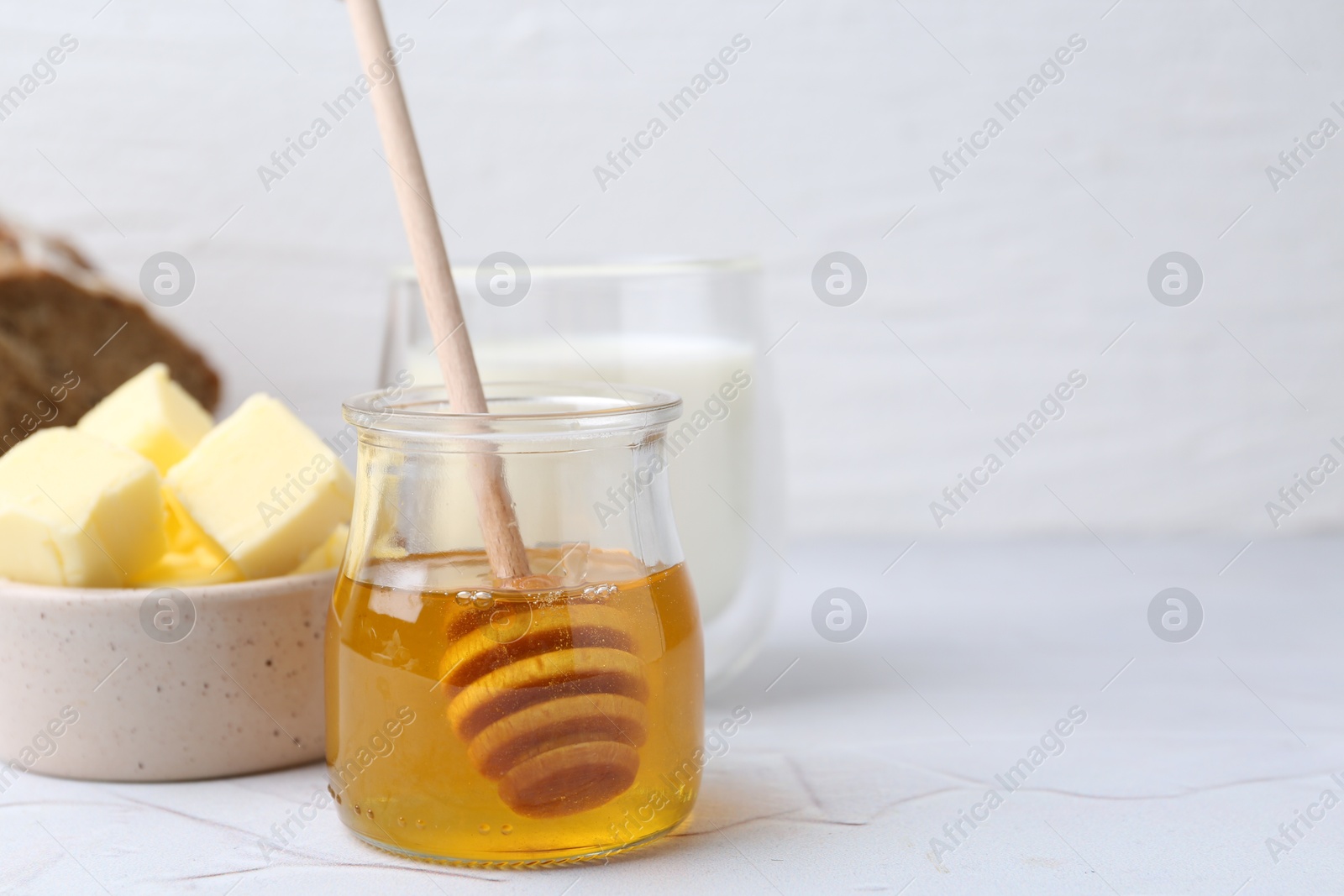 Photo of Sweet honey, butter and milk on white table, closeup. Space for text