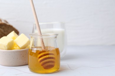 Photo of Sweet honey, butter and milk on white table, closeup. Space for text