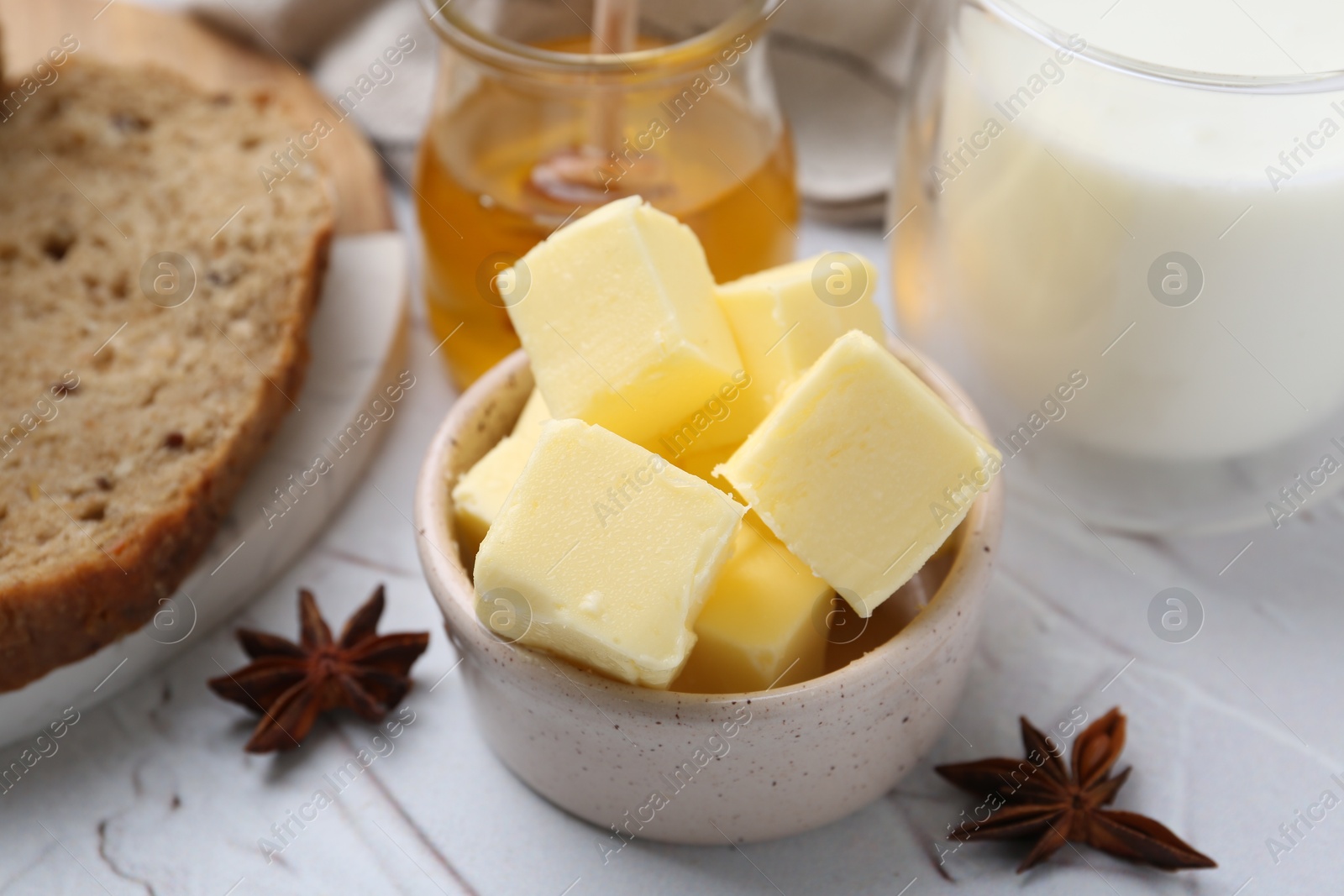 Photo of Sweet honey, butter, bread and milk on white table, closeup