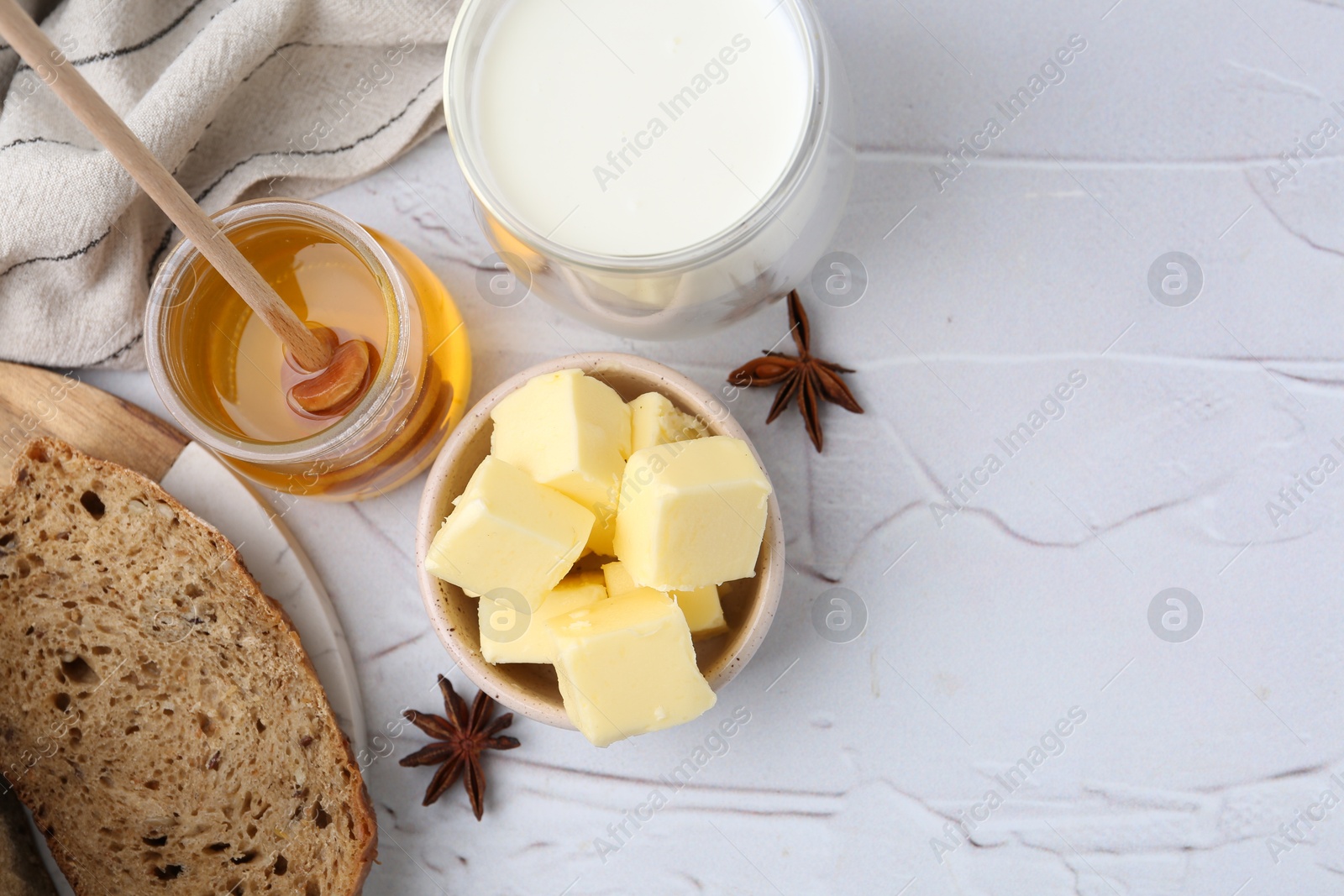 Photo of Sweet honey, butter, bread and milk on white table, flat lay. Space for text