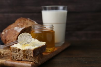 Photo of Tasty sandwich with butter, honey, dipper and milk on wooden table, closeup. Space for text