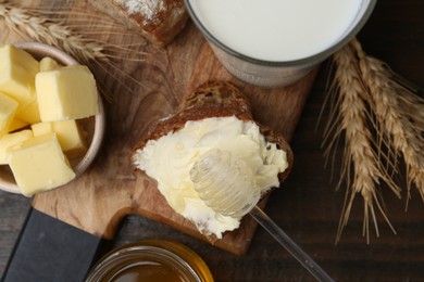 Photo of Tasty sandwich with butter, honey, dipper and milk on wooden table, flat lay