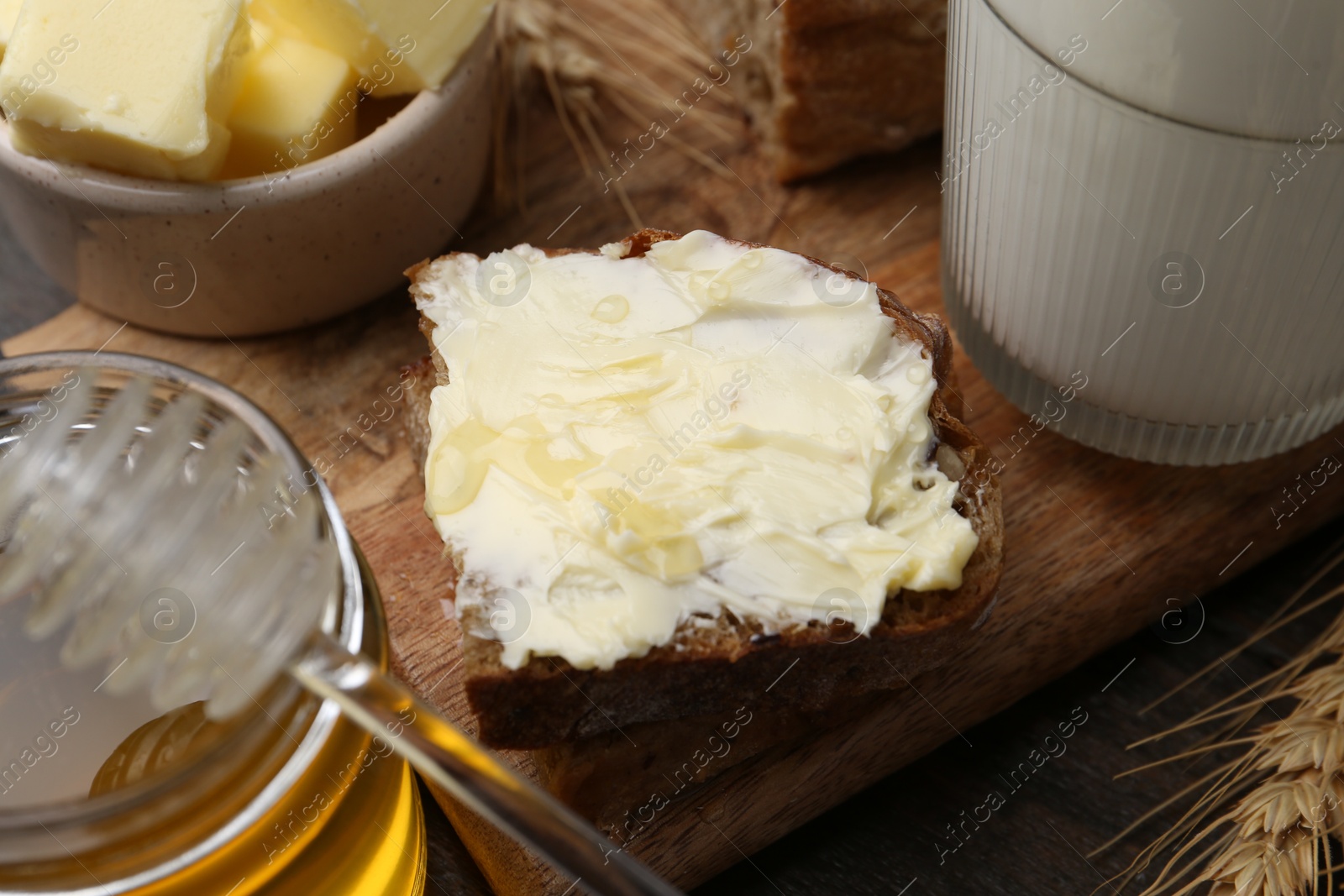 Photo of Tasty sandwich with butter, honey and milk on wooden table, closeup