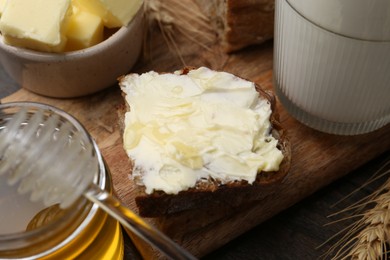 Photo of Tasty sandwich with butter, honey and milk on wooden table, closeup