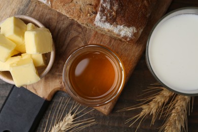 Sweet honey, butter, bread and milk on wooden table, flat lay