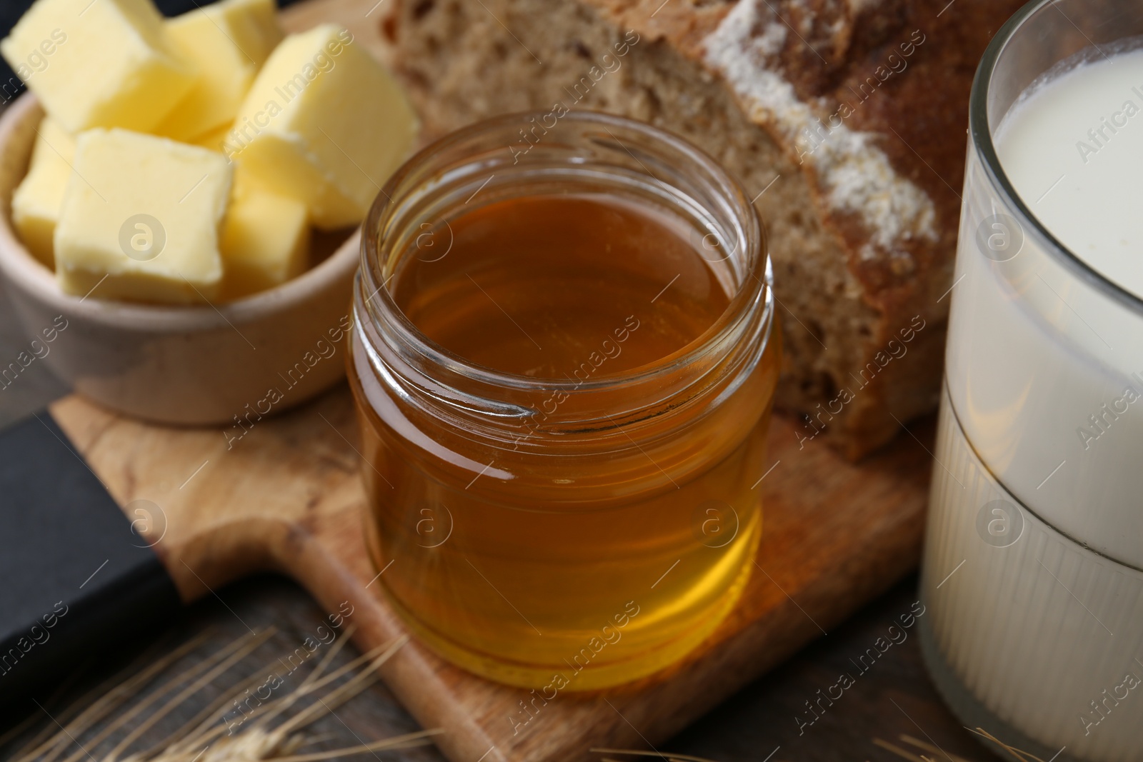 Photo of Sweet honey, butter, bread and milk on wooden table, closeup