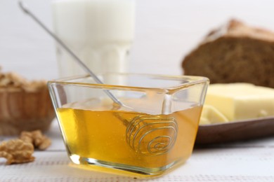 Photo of Sweet honey on white wooden table, closeup