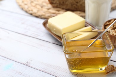 Photo of Sweet honey, butter, walnuts and milk on white wooden table, closeup. Space for text