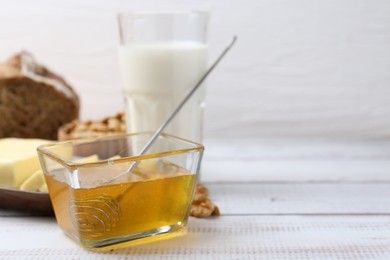 Photo of Sweet honey, butter and milk on white wooden table, closeup. Space for text