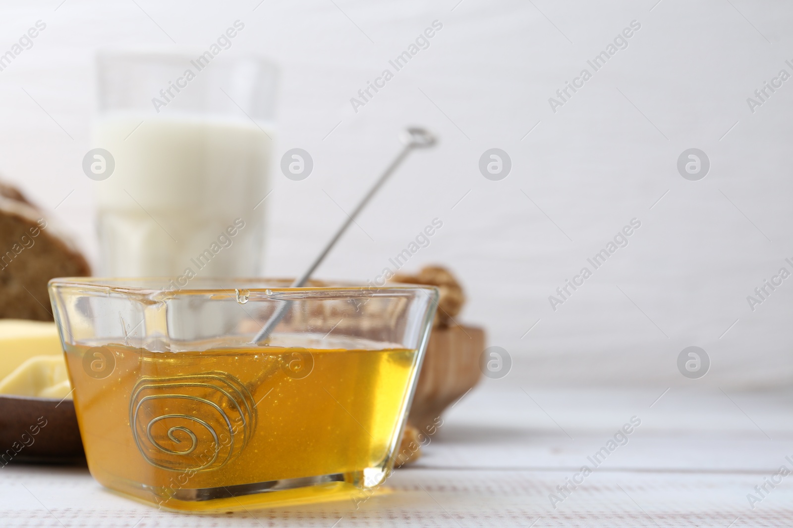 Photo of Sweet honey on white wooden table, closeup. Space for text