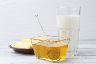 Photo of Sweet honey, butter and milk on white wooden table, closeup