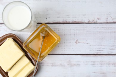 Photo of Sweet honey, butter and milk on white wooden table, flat lay. Space for text