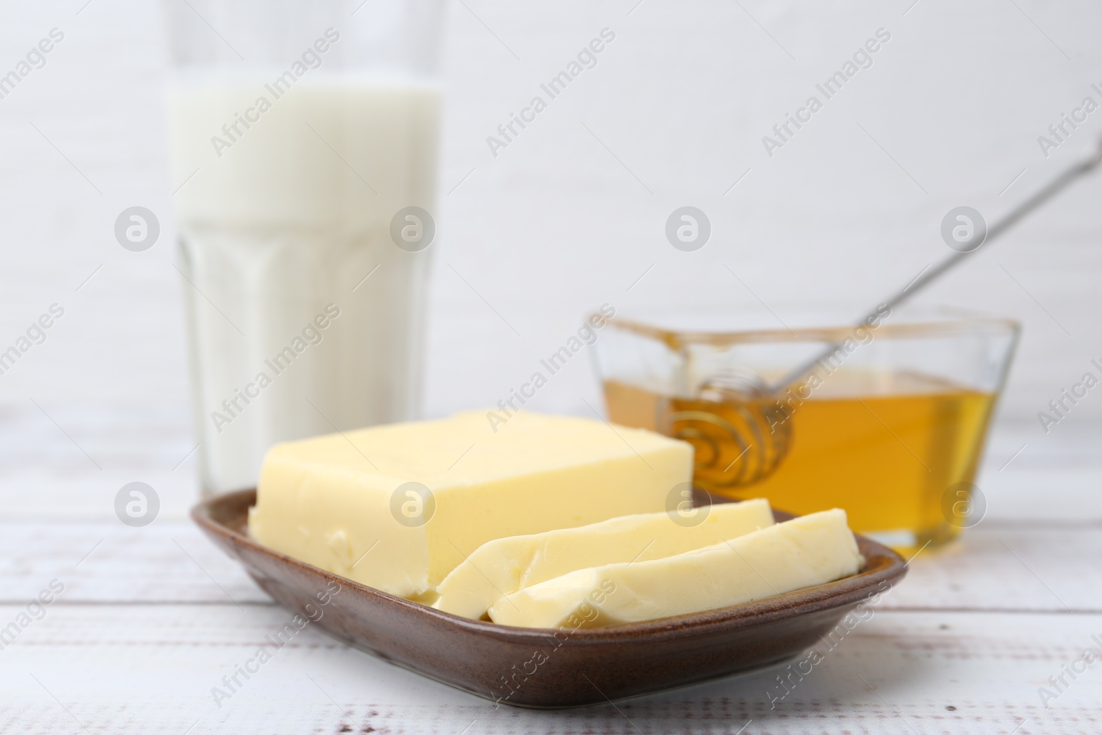 Photo of Sweet honey, butter and milk on white wooden table, closeup