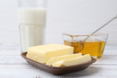 Sweet honey, butter and milk on white wooden table, closeup