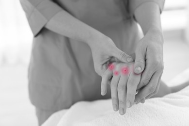 Image of Woman with joint inflammation receiving hand massage in wellness center, closeup. Black-and-white