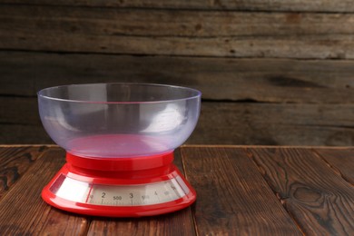 Photo of One kitchen scale on wooden table, closeup. Space for text