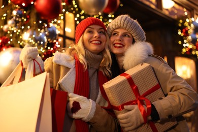 Photo of Happy friends with Christmas gift and shopping bags on city street