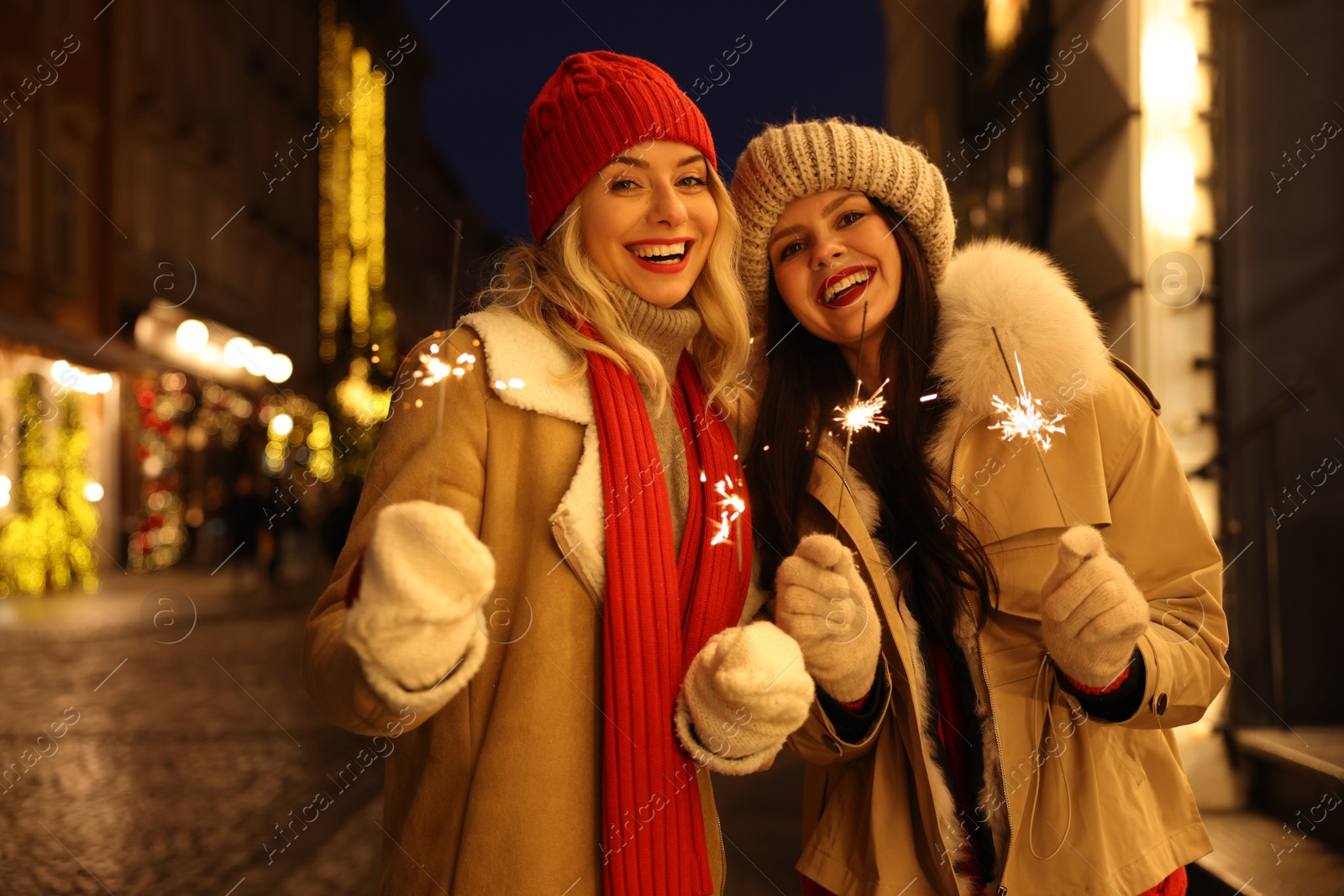 Photo of Happy friends with sparklers on city street. Christmas season