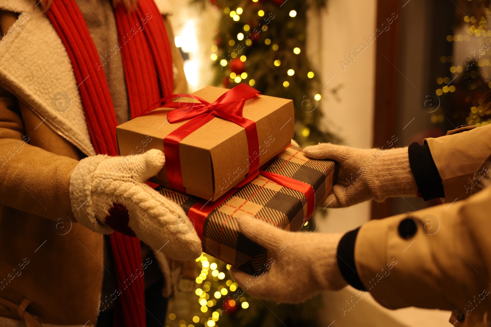 Photo of Woman receiving Christmas gifts from friend on city street, closeup