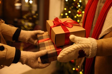 Photo of Woman receiving Christmas gifts from friend on city street, closeup