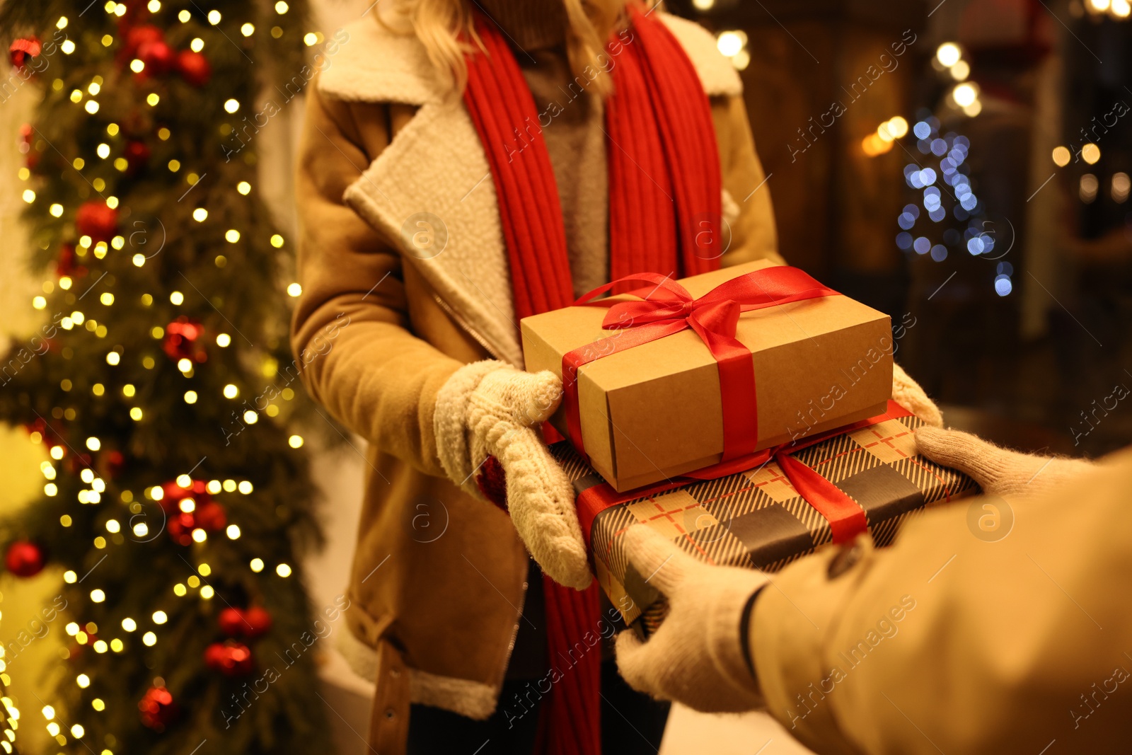 Photo of Woman receiving Christmas gifts from friend on city street, closeup