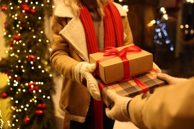 Photo of Woman receiving Christmas gifts from friend on city street, closeup