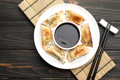 Photo of Delicious fried gyoza dumplings with sesame seeds served on wooden table, top view